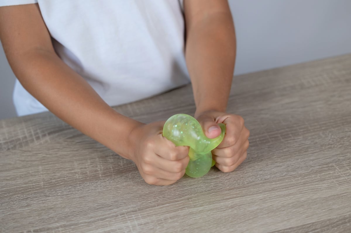 Close-up of hands squeezing a translucent green stress toy