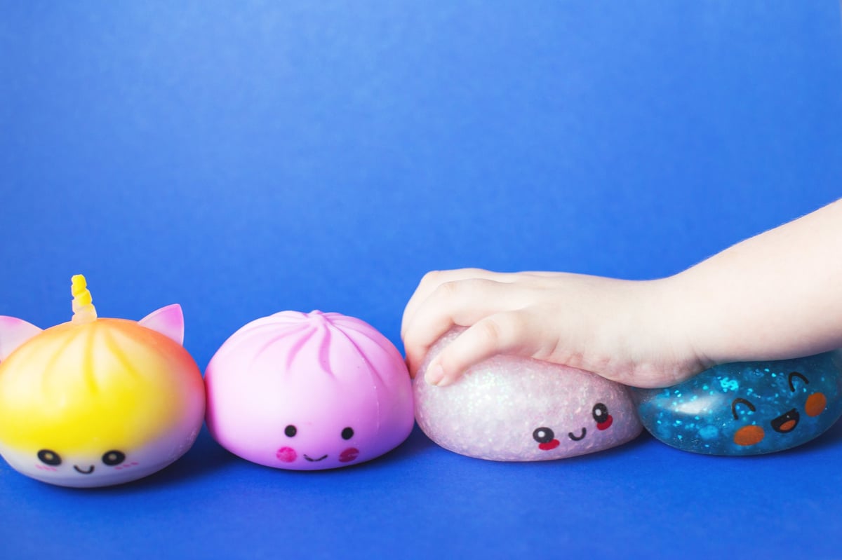 Child hand squeezing cute squishy toys for sensory play